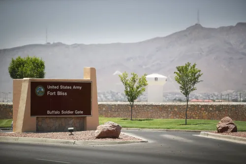 لافتة مدخل قاعدة فورت بليس العسكرية في تكساس، مع تلال خلفية، تشير إلى اعتقال جندي بتهمة التجسس.