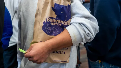 رجل يحمل حقيبة ورقية مكتوب عليها "مرحباً بكم في بلدكم" في مركز استقبال المهاجرين في غواتيمالا بعد رحلة ترحيل.