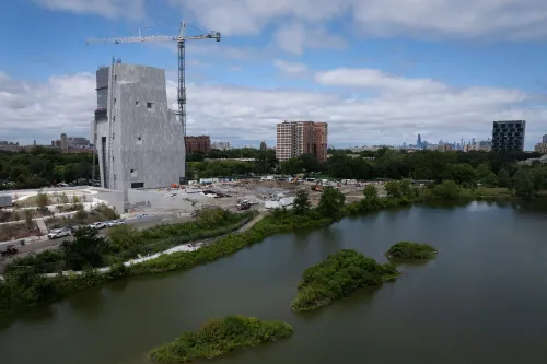 مركز أوباما الرئاسي قيد الإنشاء في شيكاغو، يظهر المبنى الحديث محاطًا بالطبيعة، مع مشهد للمدينة في الخلفية.