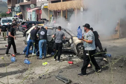 دخان يتصاعد من سيارة مدمرة بينما يحاول مجموعة من الأشخاص إخماد الحريق في منطقة الجية، بعد غارات إسرائيلية أدت إلى مقتل 15 شخصاً.