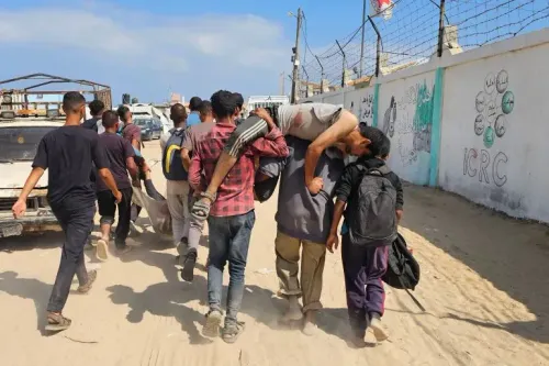 مجموعة من الشبان يحملون مصابًا في قطاع غزة، وسط مشهد مأساوي يعكس تأثير الهجمات الإسرائيلية على المدنيين أثناء محاولتهم الحصول على المساعدات.