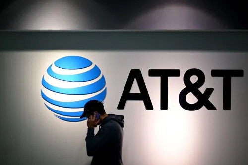 شخص يتحدث في الهاتف أمام شعار شركة AT&T، مما يعكس استثمار الشركة في تحسين شبكتها اللاسلكية.