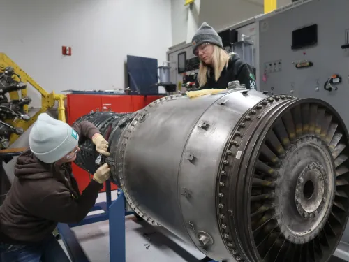 طالبات في كلية سينسيناتي ستيت التقنية يعملن على صيانة محرك طائرة، مما يعكس الطلب المتزايد على ميكانيكيي الطائرات في ظل نقص العمالة.