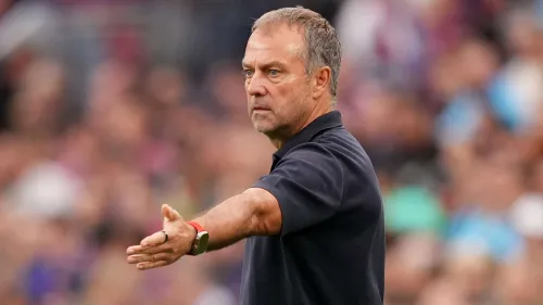 هانسي فليك مدرب برشلونة يظهر وهو يوجه تعليمات خلال مباراة، مع خلفية ضبابية للجمهور في ملعب سبوتيفاي كامب نو.