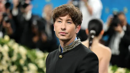 بارى كيوغان في حدث رسمي، يرتدي ملابس أنيقة، مع تعبير جاد، وسط خلفية من المصورين، استعدادًا لدوره في فيلم البيتلز.