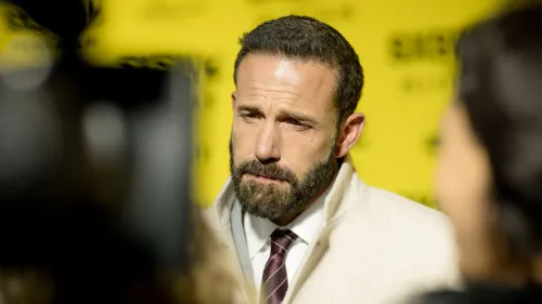 بين أفليك يظهر في حدث مع خلفية صفراء، يعكس تعابير وجهه الجادة. يتناول مواضيع حياته الشخصية والمهنية في مقابلة مع مجلة GQ.