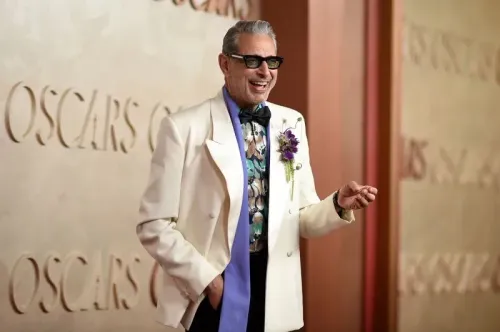 نجم هوليوود مبتسم يرتدي بدلة بيضاء مع قميص مزخرف، يتواجد على السجادة الحمراء لحفل توزيع جوائز الأوسكار 97.