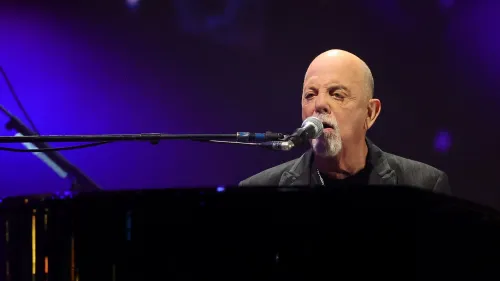 بيلي جويل يغني ويعزف على البيانو خلال عرض حي، وسط أضواء ملونة، في سياق الفيلم الوثائقي عن حياته وصراعاته.