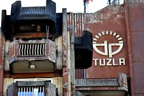 واجهة دار للمسنين في توزلا، البوسنة، تظهر الأضرار الناجمة عن حريق مميت، مع شعار "توزلا" واضح على الجدار.