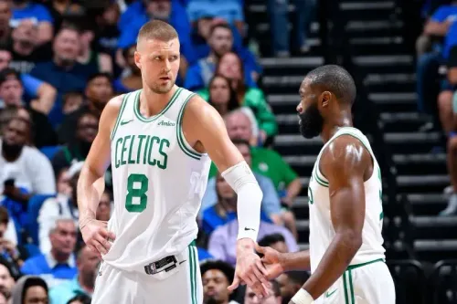 لاعبو بوسطن سيلتيكس كريستابس بورزيتشيس وجايلين براون يتواصلون خلال مباراة ضد أورلاندو ماجيك، وسط جمهور متحمس.