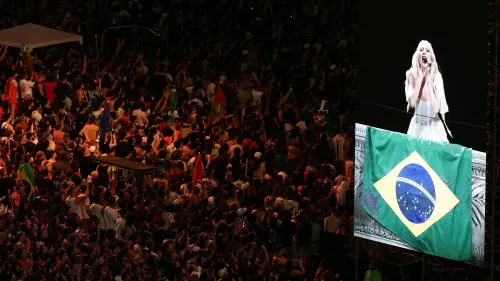 ليدي غاغا تؤدي على المسرح أمام جمهور كبير في شاطئ كوباكابانا، مع العلم البرازيلي يزين المنصة.