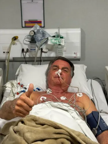 جايير بولسونارو، الرئيس البرازيلي السابق، في المستشفى بعد عملية جراحية معقدة، يظهر مبتسمًا ويرتدي أسلاك طبية.