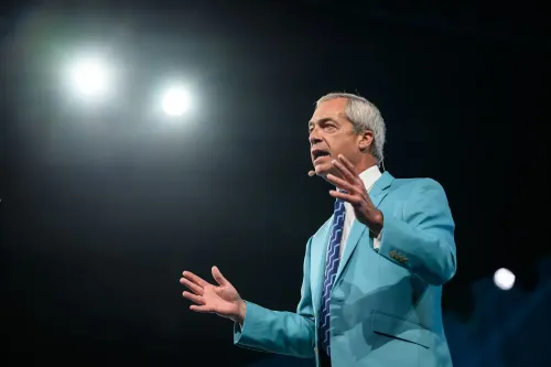 نايجل فاراج يتحدث في مؤتمر حزب الإصلاح في برمنجهام، مرتديًا بدلة زرقاء، موجهًا خطابًا حماسيًا حول قضايا الهجرة والسياسة البريطانية.