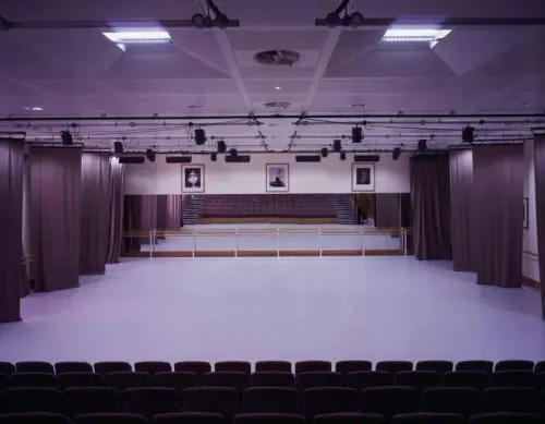 قاعة رقص فارغة في مدرسة الباليه الملكية، تظهر المرايا والستائر، تعكس بيئة تدريب راقصات الباليه الشابة.