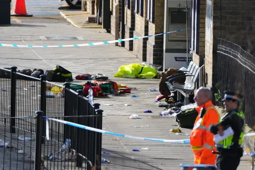 موقع الحادث في محطة قطار، يظهر فوضى مع حقائب ومعدات طبية، وضباط شرطة يتعاملون مع تداعيات هجوم طعن جماعي.