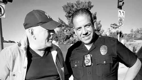 بروس ويليس يصافح ضابط شرطة في لوس أنجلوس، معبراً عن امتنانه للمستجيبين الأوائل بعد حرائق الغابات. صورة بالأبيض والأسود.
