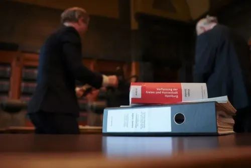 كتب قانونية ومجلدات في قاعة محكمة، مع محامين يتحركون في الخلفية، تعكس أجواء المناقشات القانونية حول حزب البديل من أجل ألمانيا.