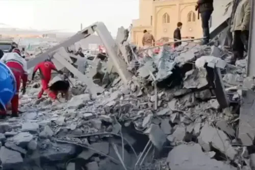 فرق الإنقاذ تعمل في موقع دمار كبير بعد غارة جوية، مع وجود أنقاض وبقايا مبنى، وأشخاص يتجولون في المنطقة.