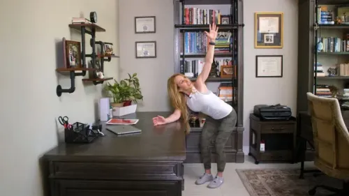 امرأة تمارس تمارين خفيفة بجانب مكتبها، مع التركيز على الحركة والنشاط البدني لتعزيز الصحة واللياقة.