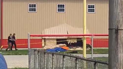 صورة لمبنى المخيم بعد اصطدام سيارة به، تظهر الأضرار الجانبية والحطام، مع وجود عناصر من خدمات الطوارئ في الموقع.