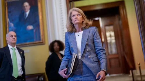 السيناتور ليزا موركوفسكي تدخل مبنى الكابيتول، تحمل مستندات، مع تعبير جاد، في سياق مناقشات حول مشروع قانون التمويل الفيدرالي لألاسكا.