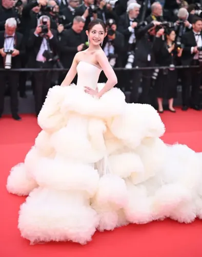 امرأة ترتدي فستانًا أبيضًا ضخمًا ومبهرًا على السجادة الحمراء لمهرجان كان السينمائي، بينما تلتقط الكاميرات صورها.