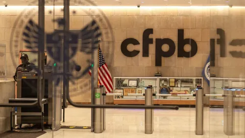 مدخل مكتب حماية المستهلك والمستهلك (CFPB) مع شعار الوكالة، حيث يُظهر حارس أمن وأعلام أمريكية، مما يعكس التحديات التي تواجه الوكالة.