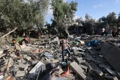 أطفال يسيرون بين الأنقاض في غزة بعد غارة جوية، مع مشاهد من الدمار في خلفية، تعكس الأزمة الإنسانية المتفاقمة في المنطقة.