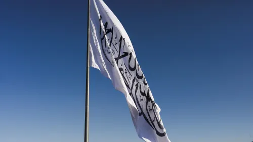 علم حركة طالبان يرفرف في السماء الزرقاء، مما يعكس الوضع السياسي المتوتر في أفغانستان وتأثير ذلك على التعليم.