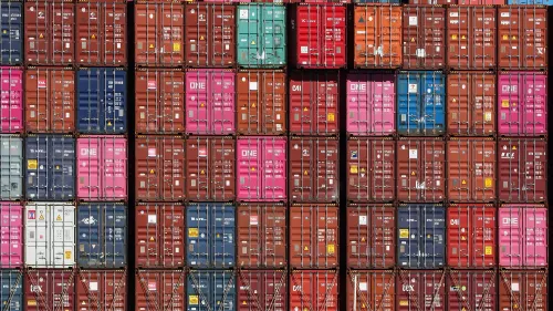 صناديق شحن ملونة م stacked في ميناء، تمثل التوترات التجارية بين الصين والولايات المتحدة نتيجة الرسوم الجمركية المتزايدة.
