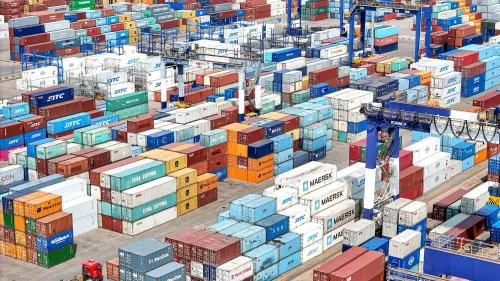 صورة لميناء حاويات مزدحم، حيث تتكدس حاويات الشحن المتنوعة، تعكس تأثير الرسوم الجمركية المتبادلة بين الصين والولايات المتحدة.