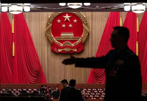 شخصيات تتجول في قاعة احتفالية تحمل شعار الصين، مع ستائر حمراء خلفية، تعكس الأجواء الرسمية للمؤتمر الشعبي الوطني.