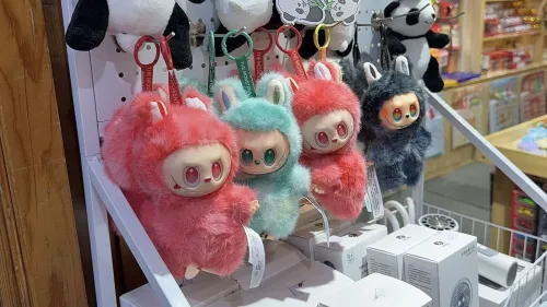 دمى "لافوفو" الملونة والمعلقة في متجر، تظهر بأشكال غريبة وجذابة، تعكس شعبية الدمى المقلدة في الأسواق الصينية.