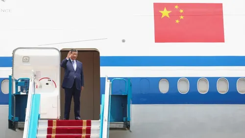 شي جين بينغ يحيي الحضور عند نزوله من الطائرة في فيتنام، مع العلم الصيني واضح خلفه، في بداية جولة دبلوماسية لتعزيز التجارة.