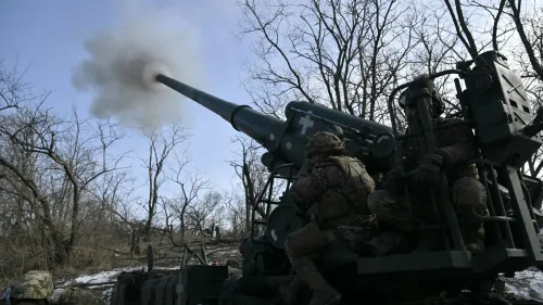 جنود أوكرانيون يقومون بتشغيل مدفع ميداني في منطقة مشجرة، مع تصاعد الدخان من فوهة المدفع، في سياق الصراع العسكري الحالي.