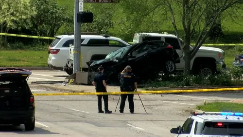 حادث سير يظهر سيارة سوداء متضررة ترتفع فوق الرصيف، مع وجود ضباط شرطة في موقع الحادث، حيث وقع الحادث بالقرب من جامعة سينسيناتي.