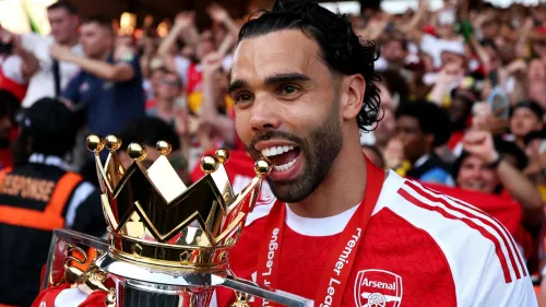 ديفيد رايا حارس مرمى أرسنال يحتفل بفوزه بلقب الدوري الإنجليزي الممتاز مع كأس القفاز الذهبي في يداه وسط جماهير متحمسة.
