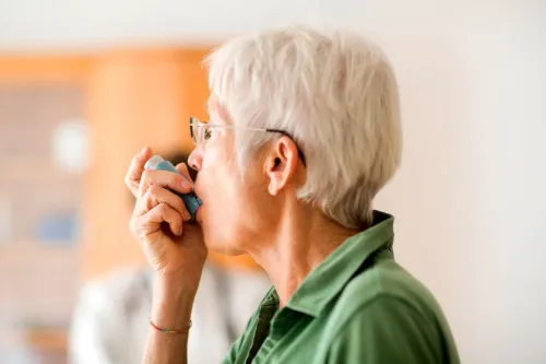 امرأة مسنّة تستخدم جهاز استنشاق لعلاج الربو، مما يعكس تأثير تغير المناخ على صحة الرئة وزيادة الانبعاثات.