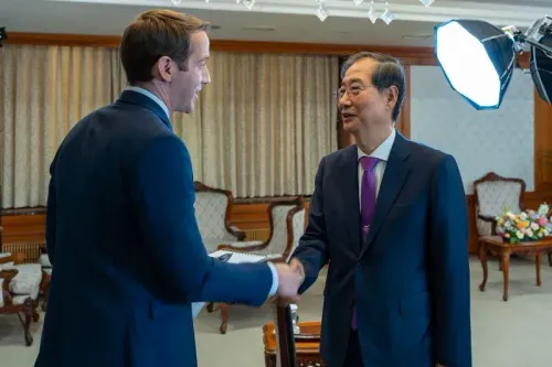 رئيس الوزراء الكوري الجنوبي هان داك سو يتحدث مع مسؤول أمريكي خلال اجتماع رسمي، مع خلفية من الأثاث التقليدي.