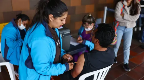 موظف صحي يعطي لقاح الحمى الصفراء لرجل في مركز تطعيم، مع وجود أشخاص آخرين في الخلفية ينتظرون دورهم.