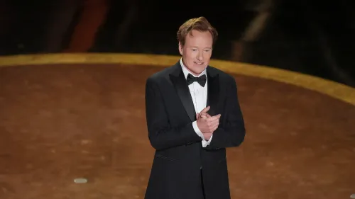 كونان أوبراين يرتدي بدلة رسمية ويقف مبتسمًا على المسرح خلال حفل توزيع جوائز الأوسكار، حيث سيعود لتقديم الحفل في دورته الـ 98.