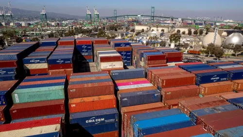 صورة تظهر حاويات شحن ملونة في ميناء مزدحم، تعكس التوترات الاقتصادية وتأثيرها على التجارة الأمريكية.