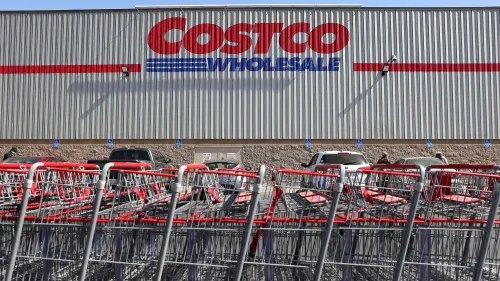 مدخل متجر كوستكو مع شعار الشركة واضحاً، بينما تُركت عربات التسوق الحمراء متراصة في الجهة الأمامية.