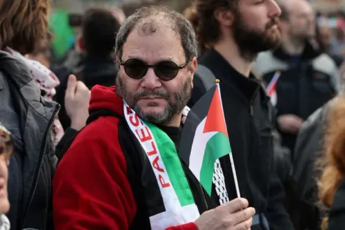 رجل يحمل علم فلسطين ويرتدي وشاحاً يحمل اسم فلسطين خلال تجمع احتجاجي ضد الاستيطان الإسرائيلي في الضفة الغربية والقدس الشرقية.