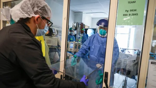 عامل صحي يرتدي معدات واقية ينقل جهاز طبي إلى غرفة مريض في مستشفى، في إطار جهود مواجهة الأوبئة وتعزيز التعاون الصحي العالمي.