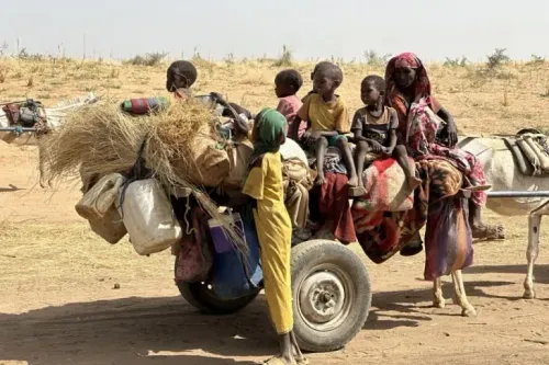 مجموعة من الأطفال والنساء يجلسون على عربة تجرها حيوانات في منطقة قاحلة، تعكس آثار النزاع في دارفور.