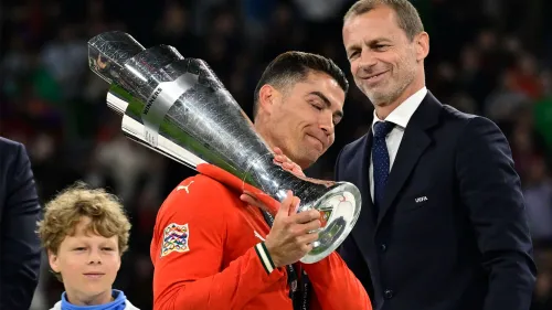 كريستيانو رونالدو يحمل كأس دوري الأمم الأوروبية بفخر بعد فوز البرتغال، مع حضور مسؤول يويفا بجانبه.