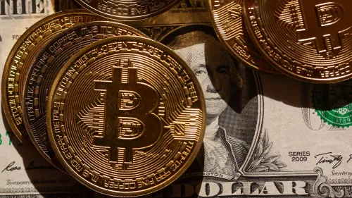 عملات بيتكوين ذهبية تتواجد فوق ورقة نقدية من الدولار الأمريكي، مما يرمز إلى تزايد اهتمام الحكومة الأمريكية بالعملات الرقمية.