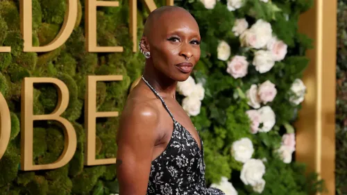 سينثيا إريفو تتألق بفستان أنيق خلال حدث، مع خلفية مزهرة، حيث تم الإعلان عن استضافتها لحفل توزيع جوائز توني.