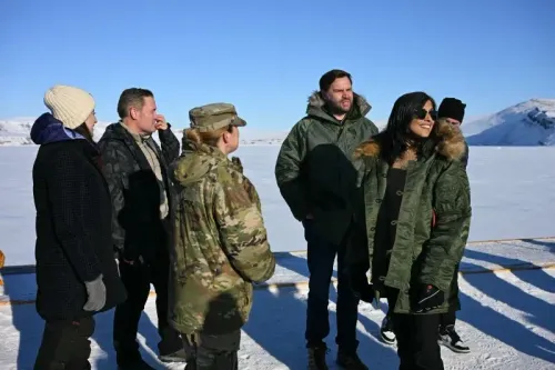 مجموعة من الأشخاص يرتدون ملابس دافئة يتحدثون في منطقة جليدية في غرينلاند، مع خلفية جبلية في يوم مشمس، تعبيرًا عن التعاون الأمني.